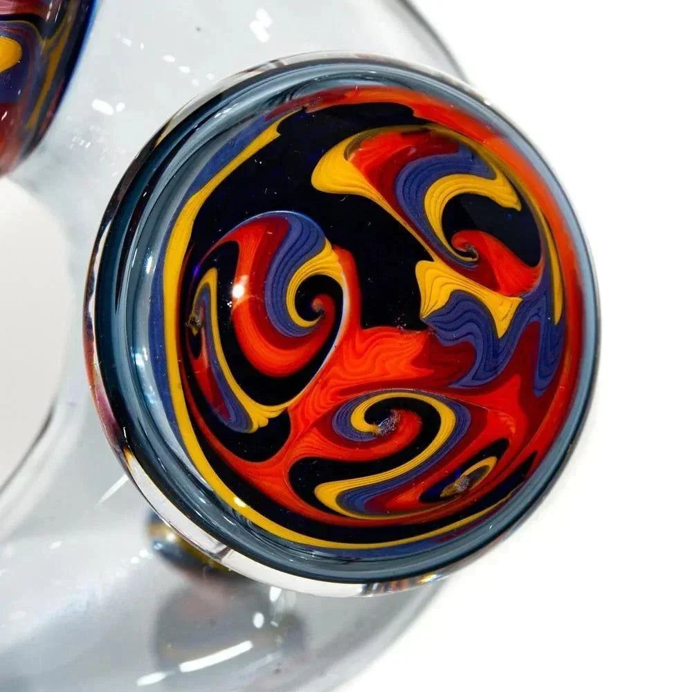 Close-up of a glass pipe with vibrant orange, yellow, red, blue, and black swirl design.