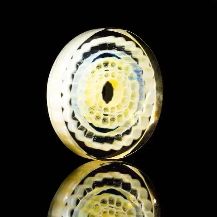 Intricate heady glass pipe bowl with yellow, black, and white spiral patterns on reflective surface