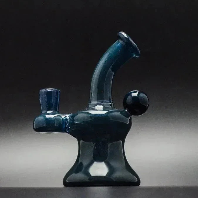 Deep blue glass bubbler pipe with curved neck and spherical carb cap, studio-lit against dark background