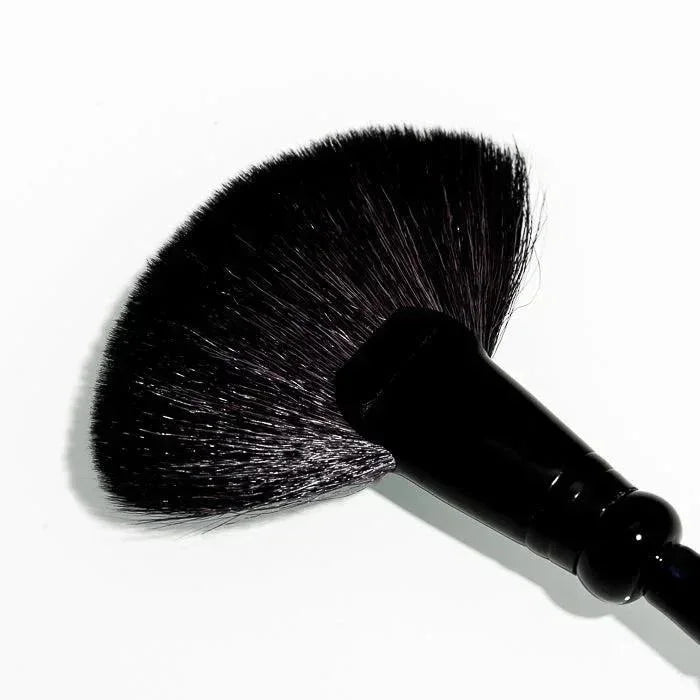 Black fan-shaped makeup brush with sleek handle on white background