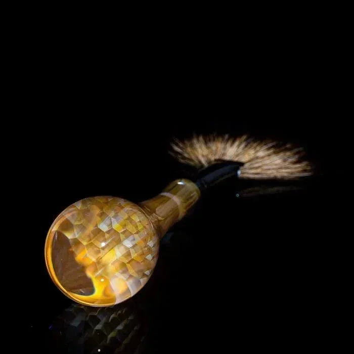 Faceted amber glass pipe with brush attachment, studio black background