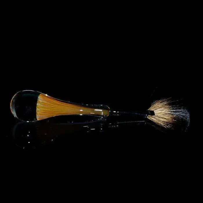 Glass pipe with amber accents and brush-like end, sleek design on black background