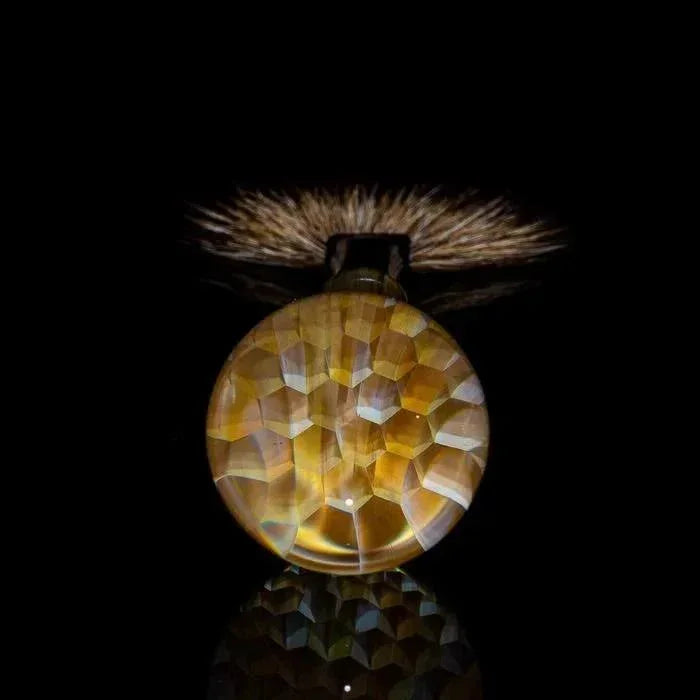 Faceted amber glass pipe with textured grip, studio-lit against black background