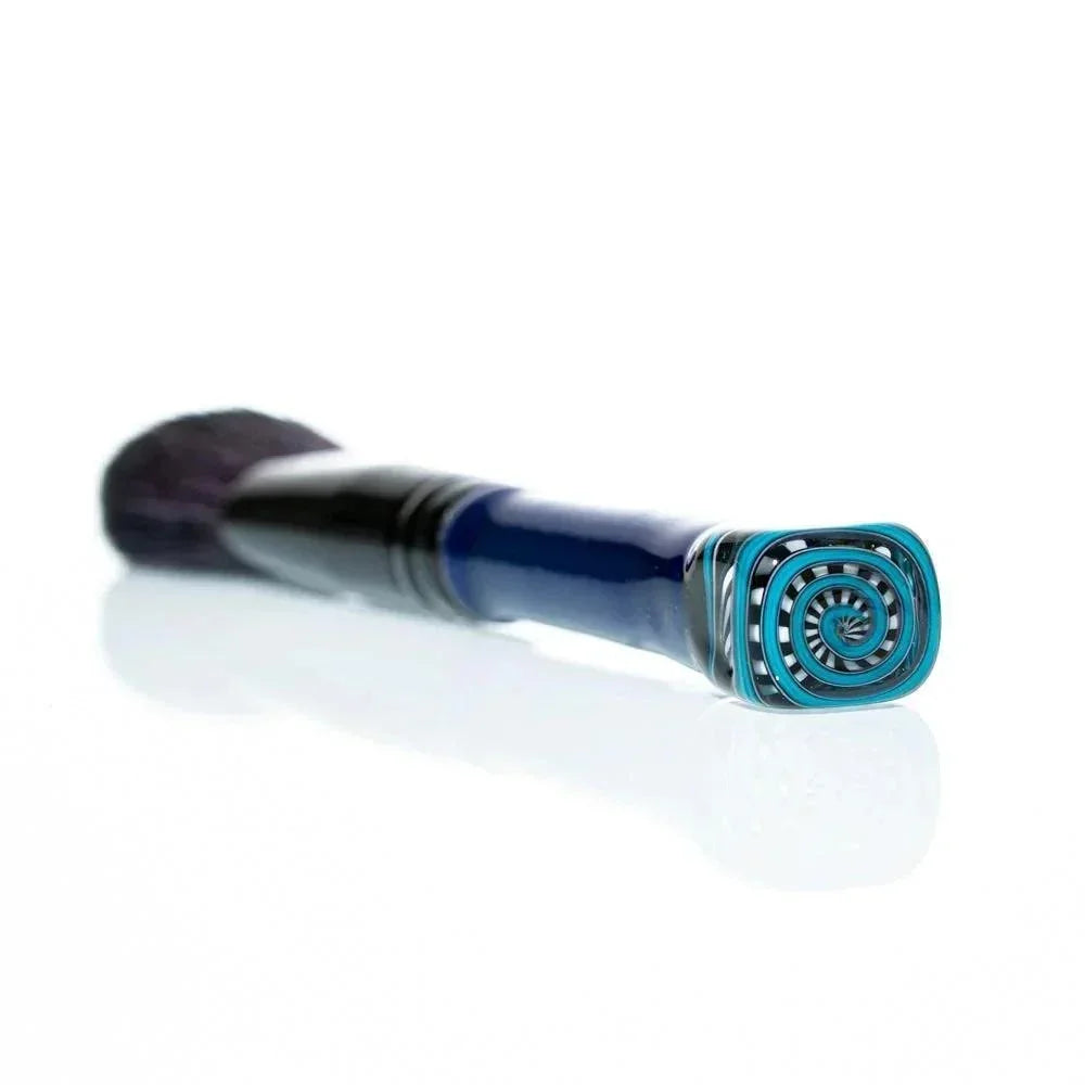 Blush makeup brush with blue glass handle and spiral patterned end on white background