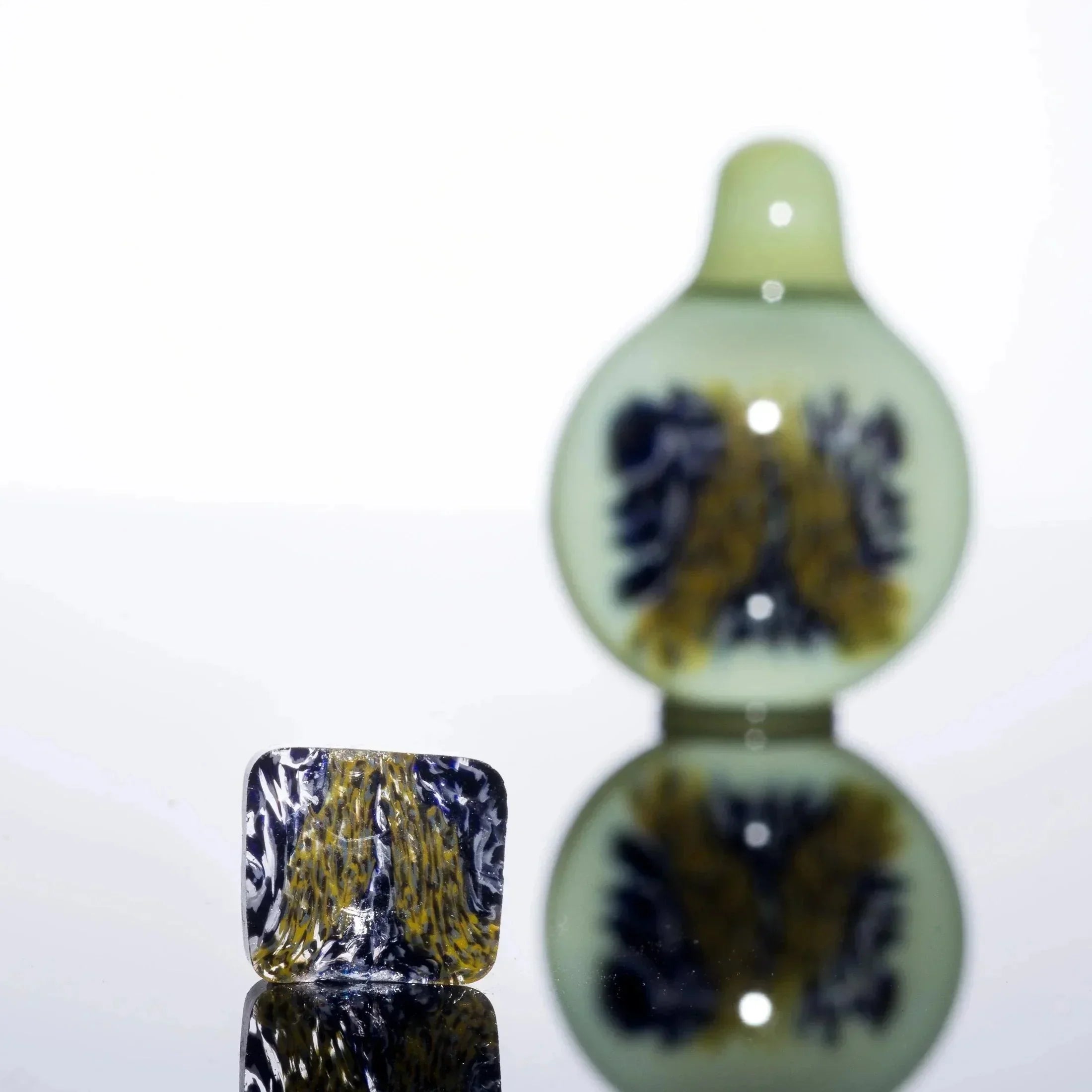 Handblown glass pipe with blue and gold swirls, artisan heady glass accessory on reflective surface