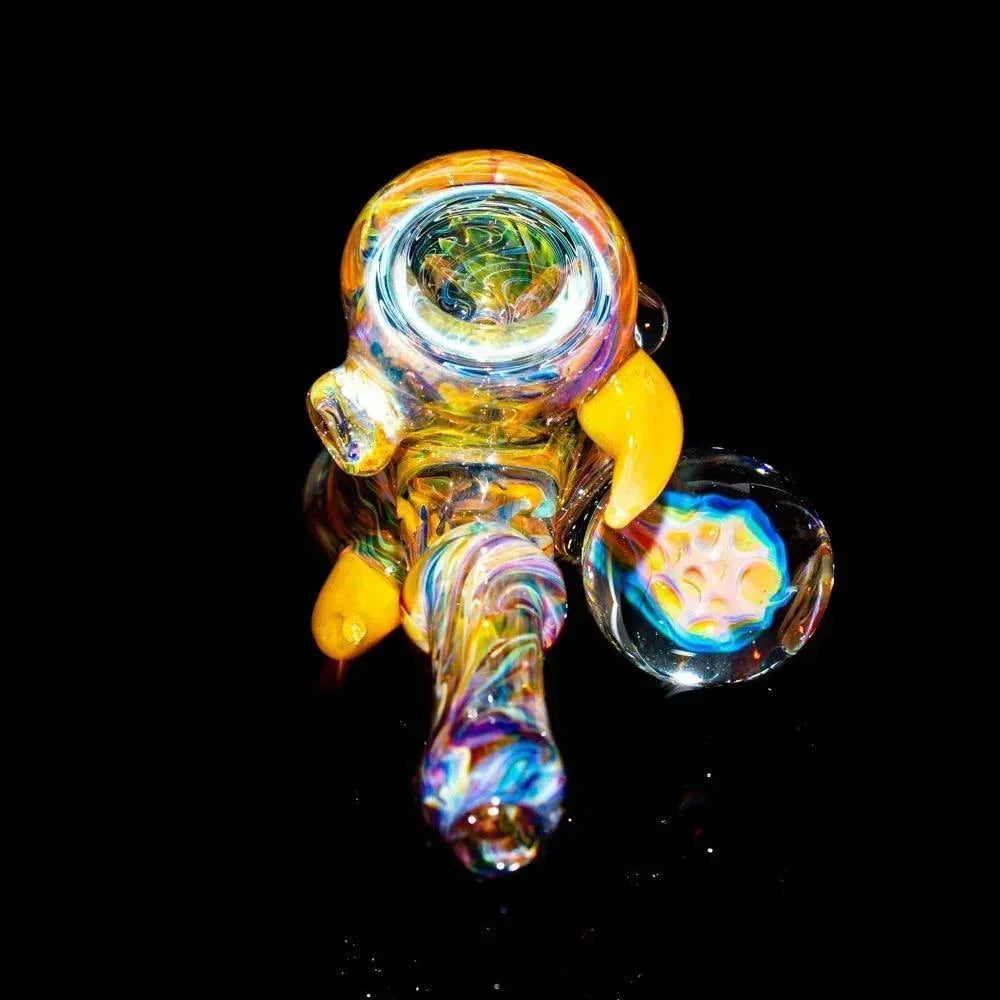 Colorful heady glass hand pipe with yellow accents and intricate details on black background