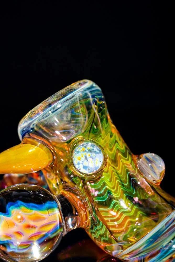 Colorful heady glass pipe with intricate patterns and marbles on a black background