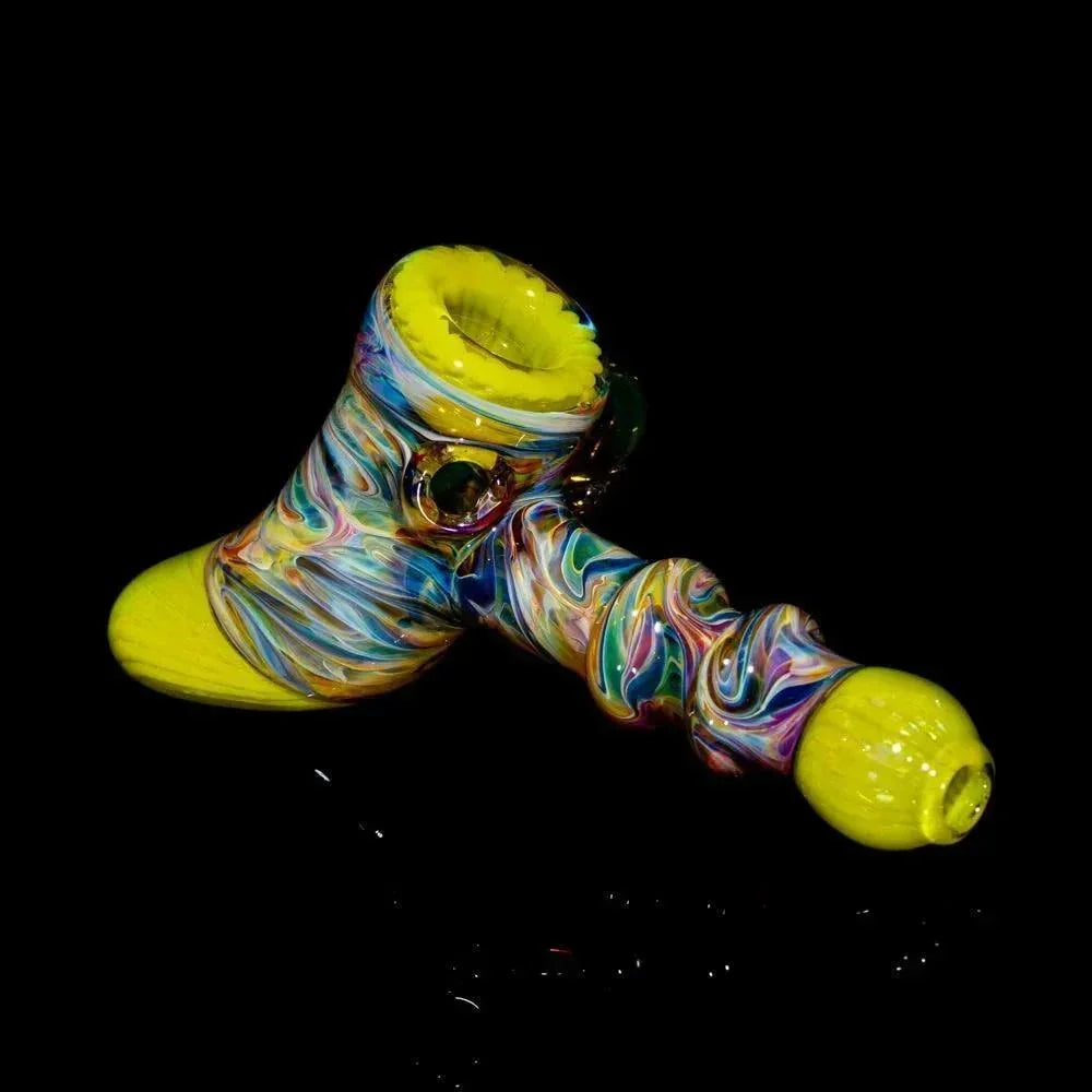 Colorful hand-blown glass hammer pipe with yellow ends on black background