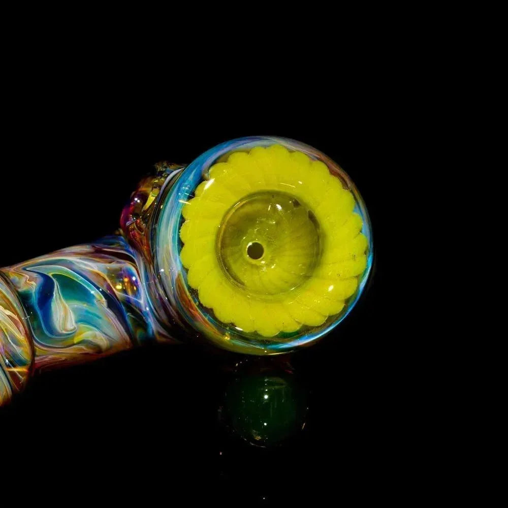 Heady glass hammer pipe with vibrant swirled colors and a yellow decorative bowl on black background.