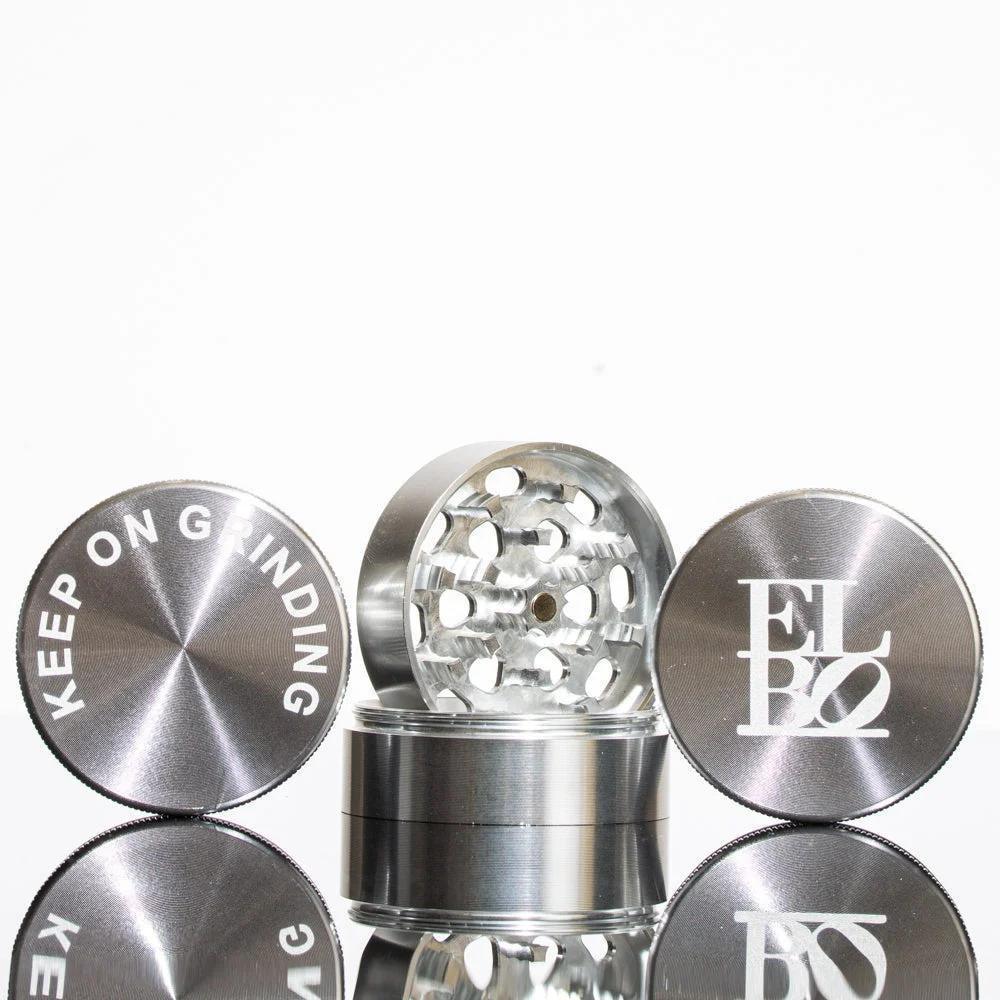 Silver four-piece herb grinder with engraved top, sharp teeth, and reflective finish