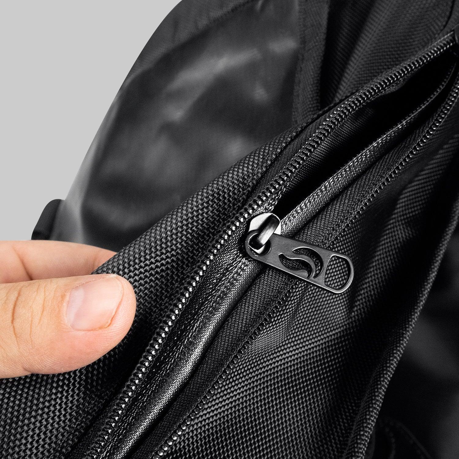 Close-up of a hand holding a black textured backpack with a zipper pocket