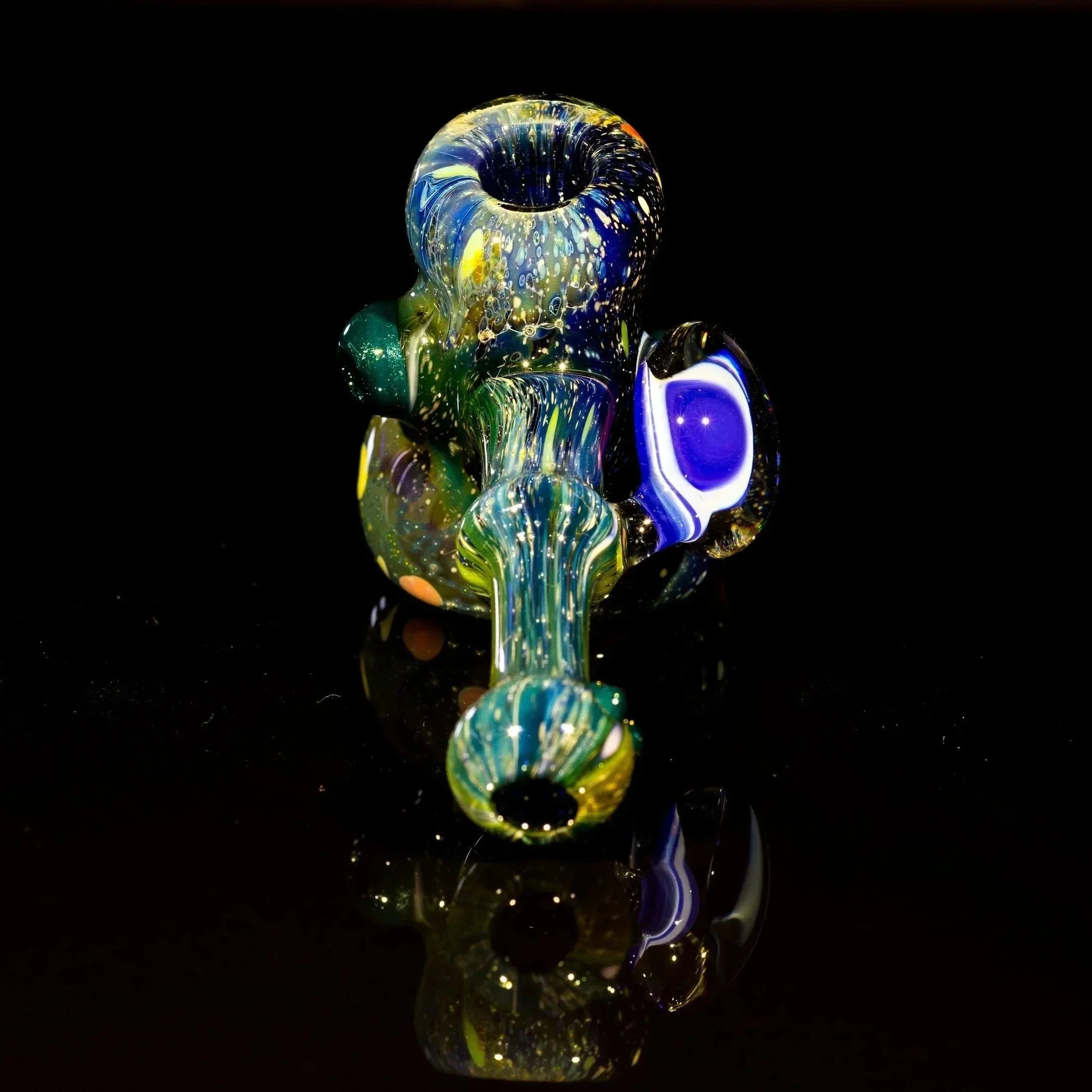 Colorful heady glass pipe with swirls and speckles, reflecting on black surface