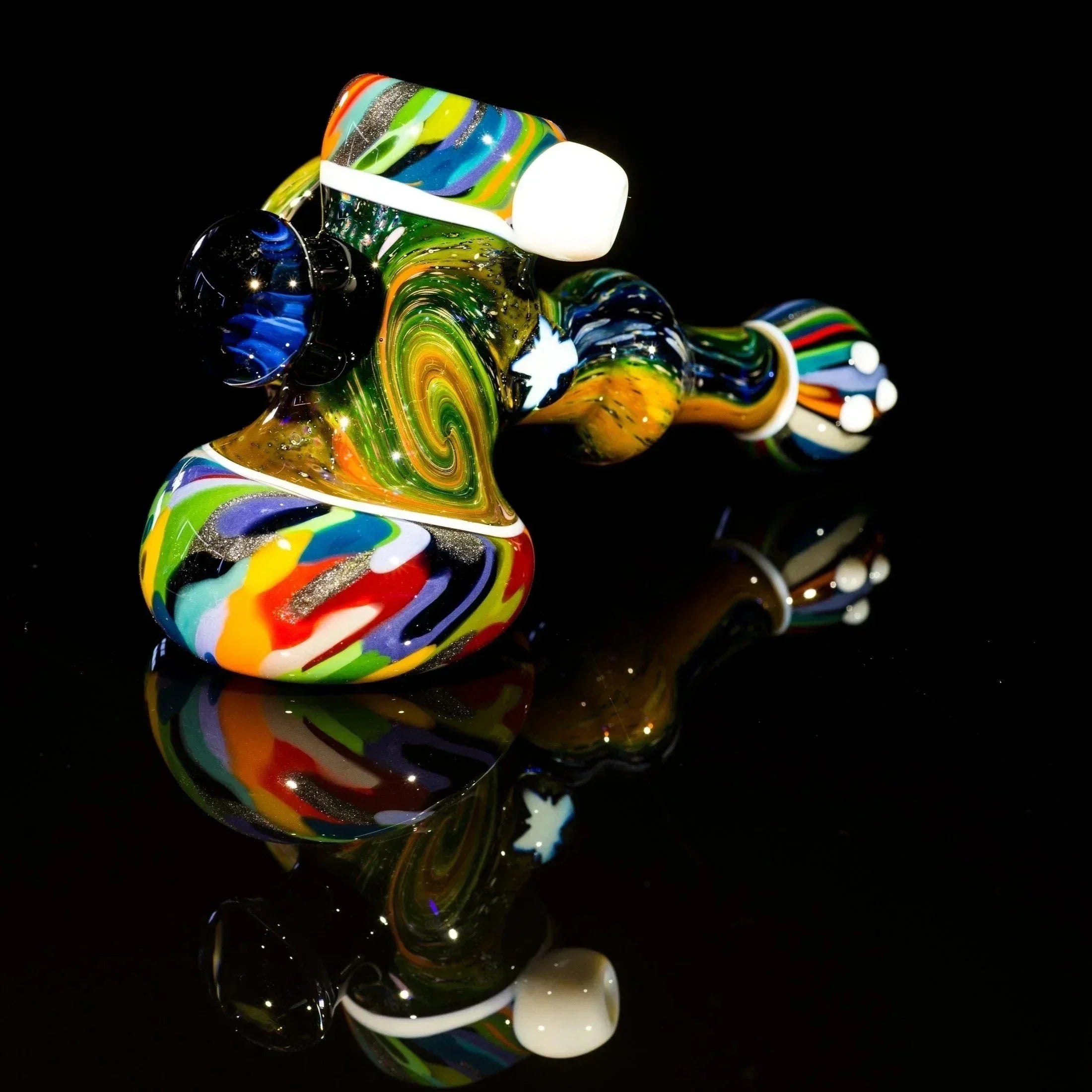Colorful swirled glass pipe with glitter accents, reflective black surface, heady glass art