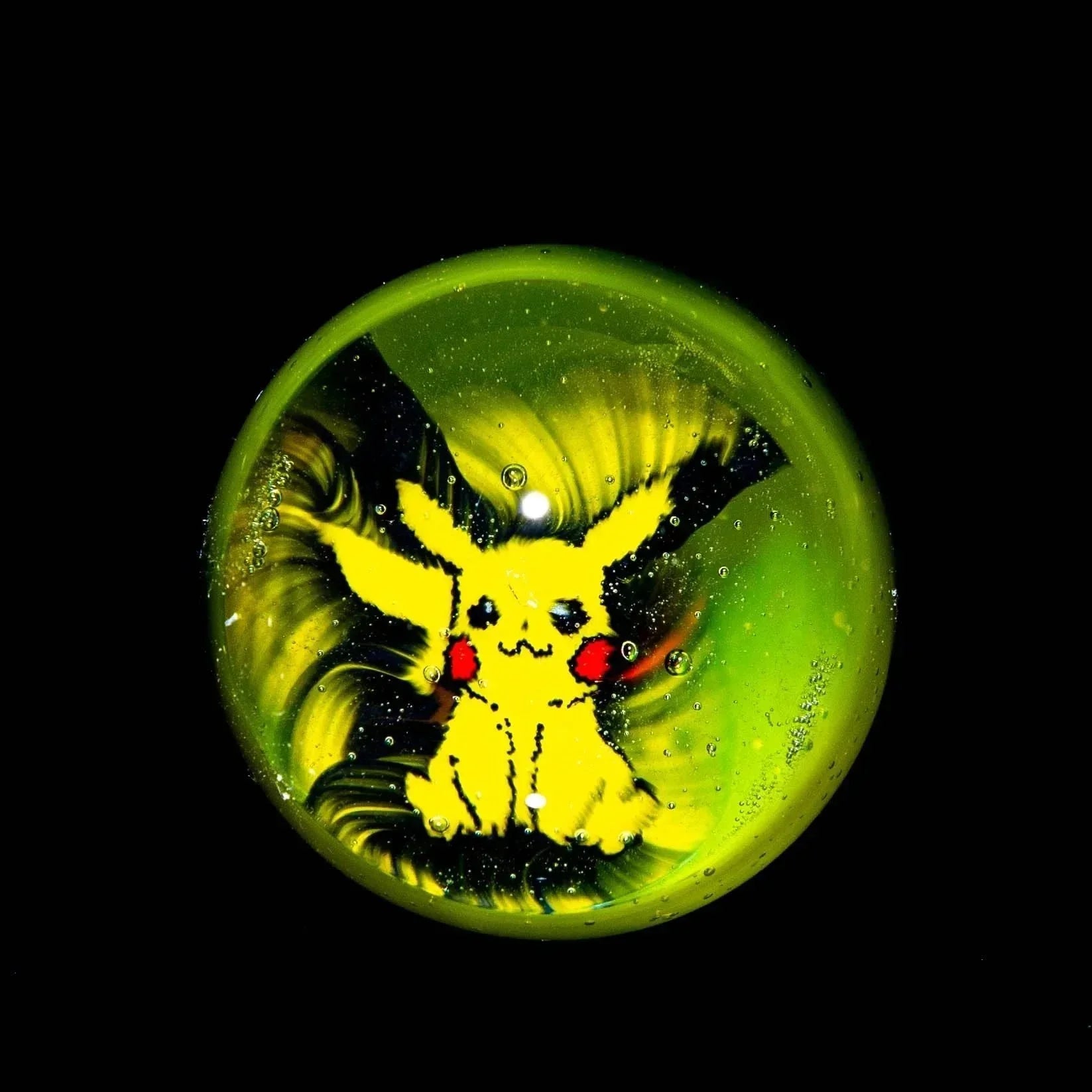 Glass marble featuring a yellow Pikachu design with swirling green background.