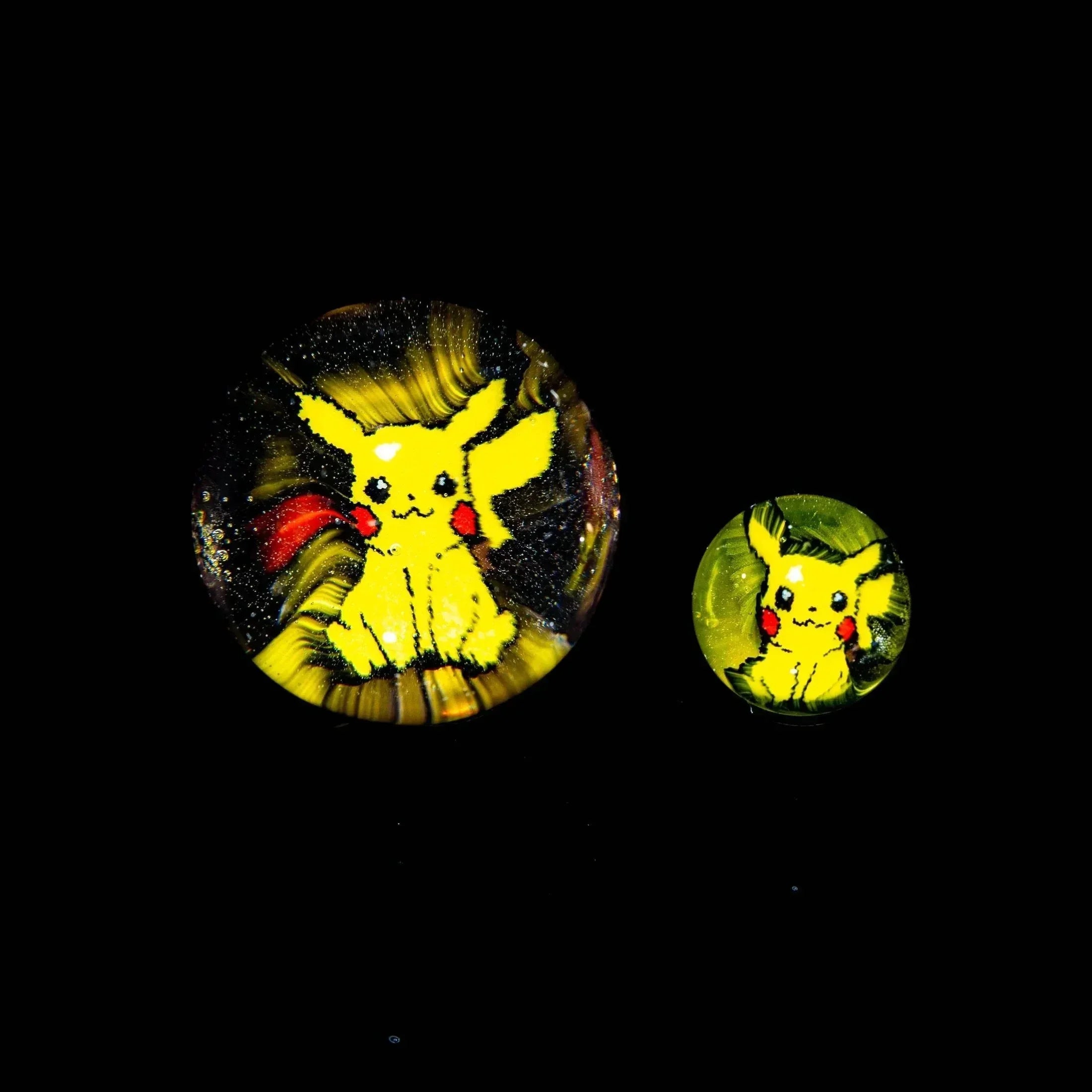 Two handmade glass marbles with cartoon yellow mouse design on a black background.