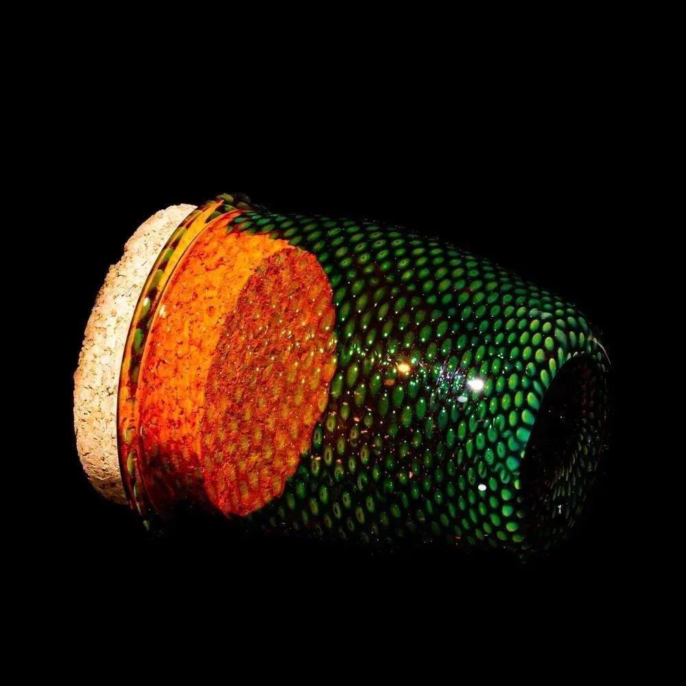 Handblown glass jar with green snakeskin pattern and cork lid on black background