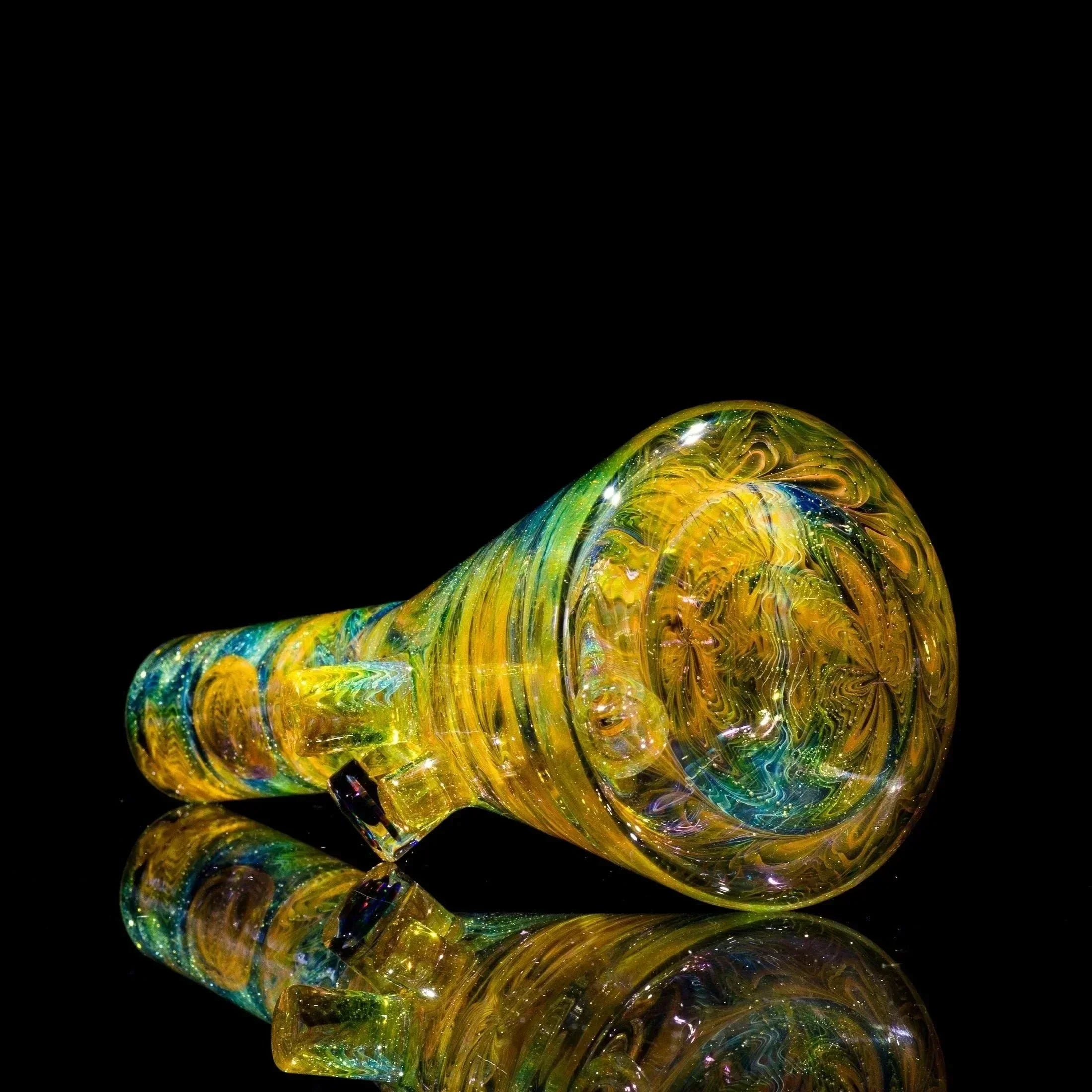 Vibrant yellow and green swirled glass pipe with glitter, reflecting on black surface
