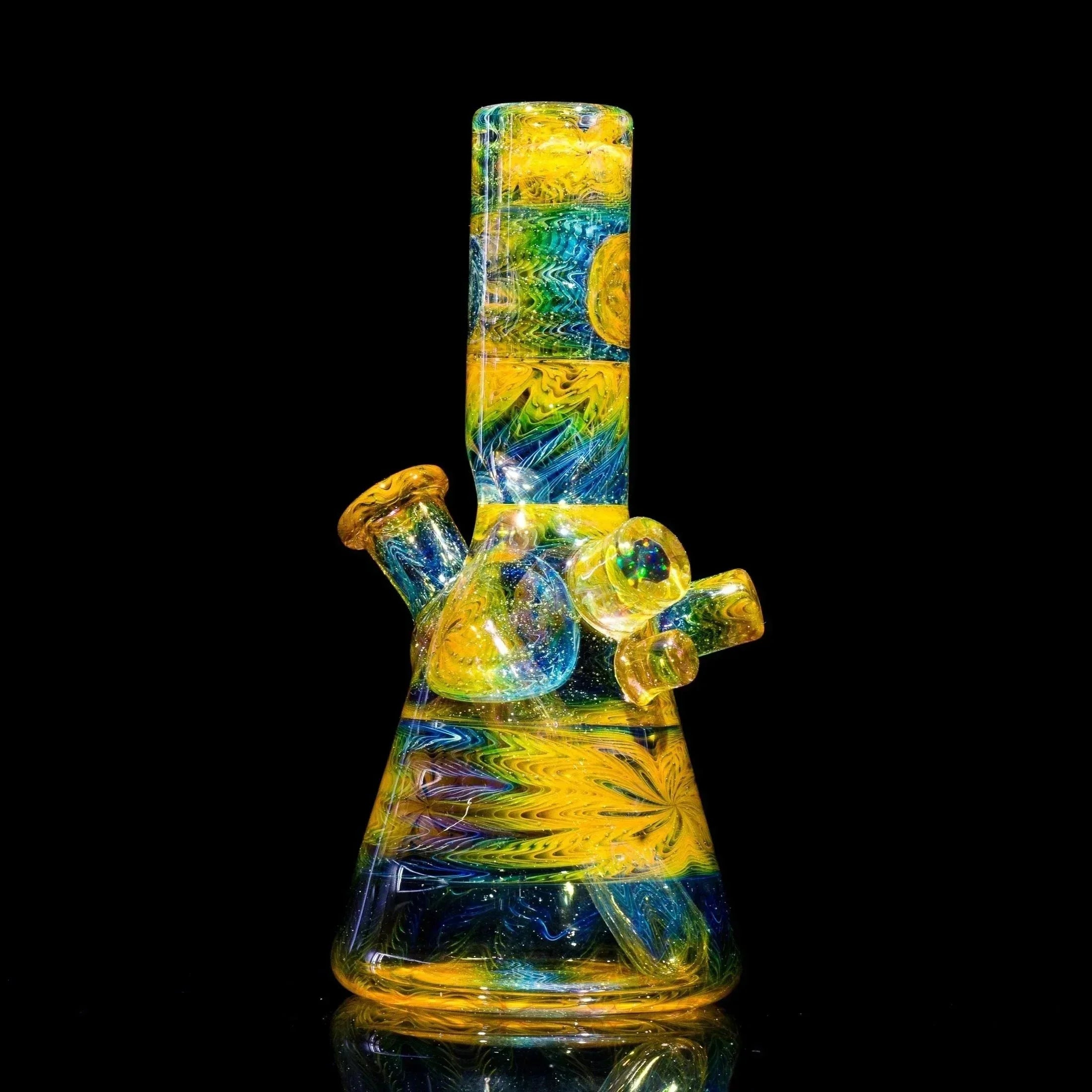 Vibrant yellow, blue, and green swirls adorn this heady glass bong with intricate patterns and a reflective base.
