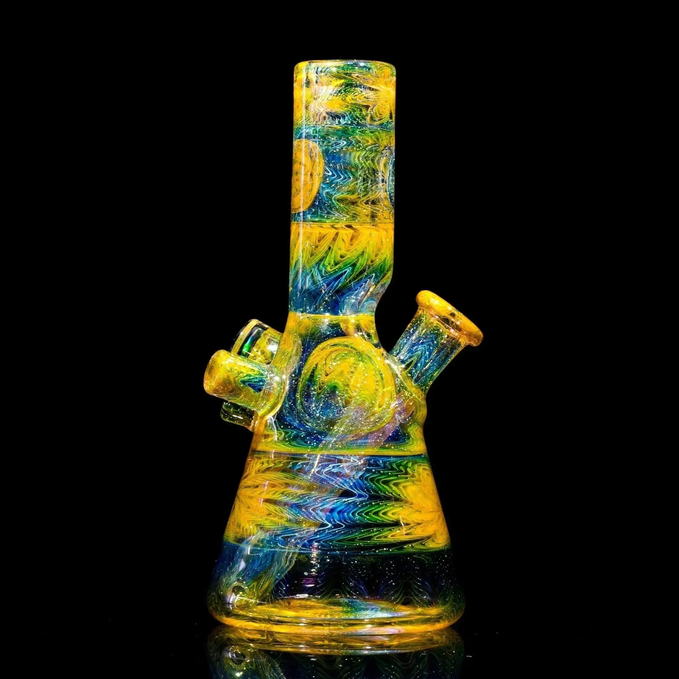 Vibrant yellow, blue, and green swirled glass bong with glitter accents, showcasing heady glass artistry.