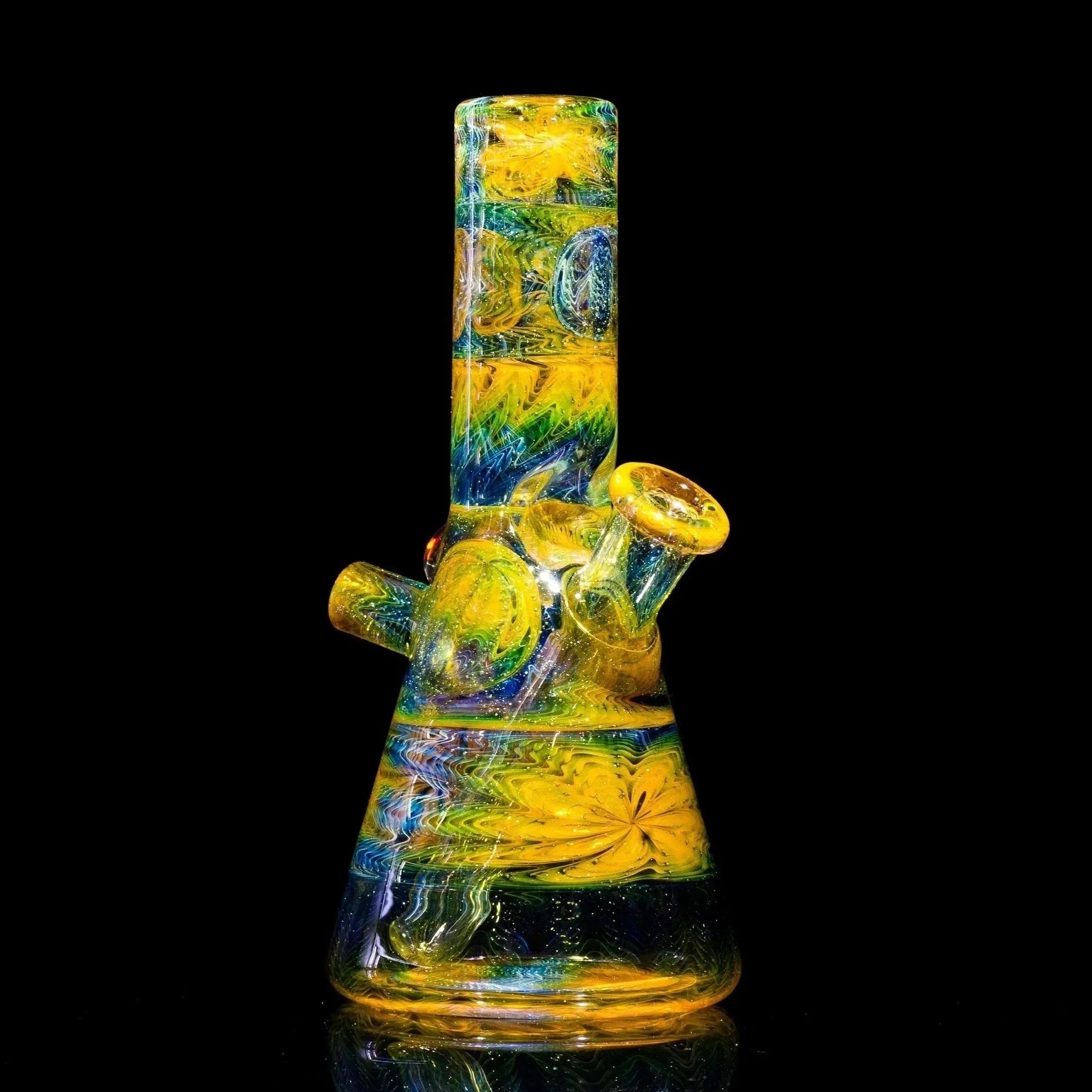 Vibrant yellow, green, and blue swirls adorn this artistic glass bong with floral accents and glittery details.