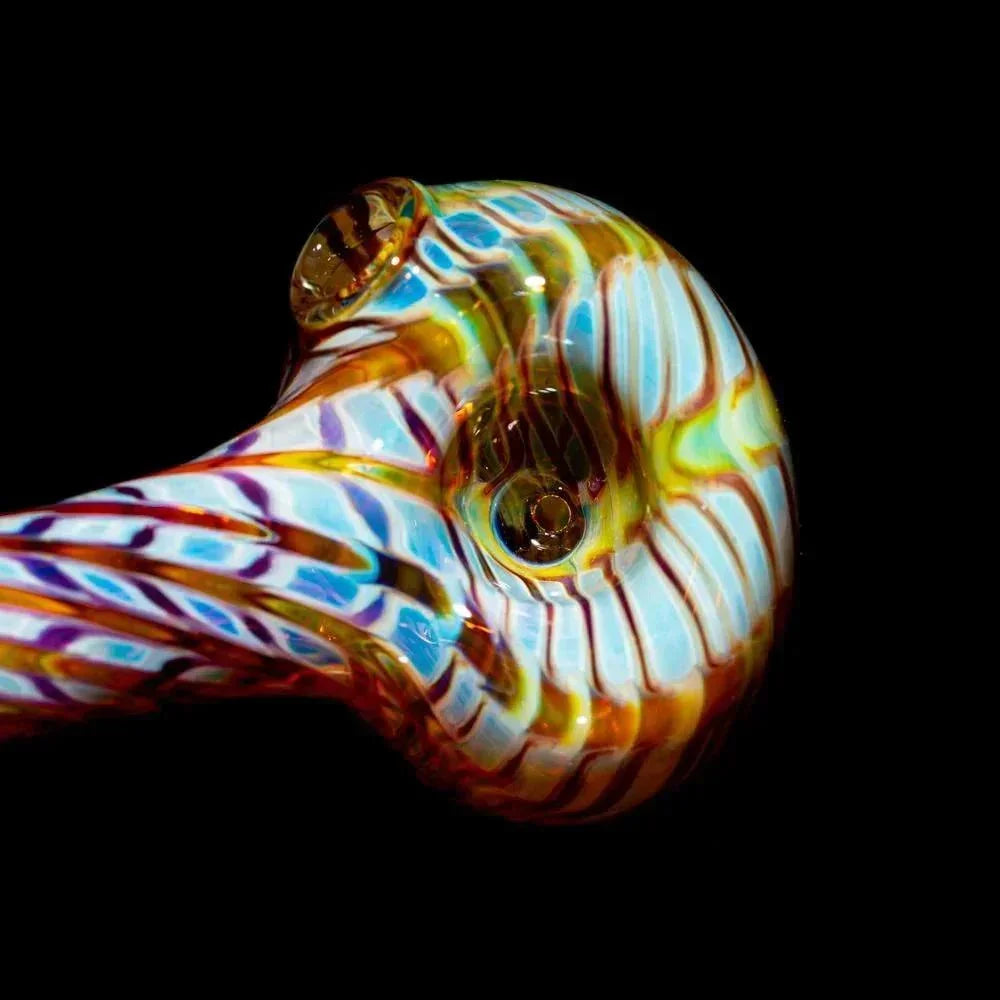 Close-up of a colorful hand-blown glass pipe with amber and purple swirls on black background.