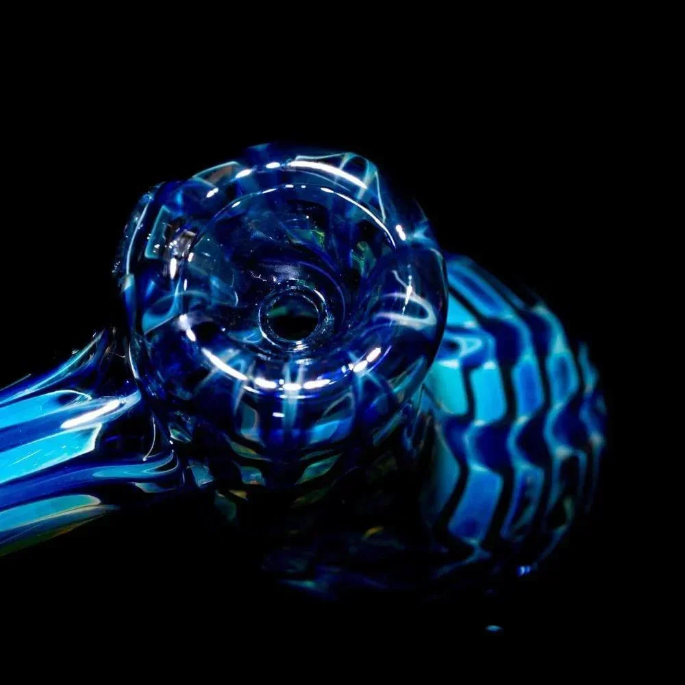 Close-up of a blue patterned glass hand pipe with intricate swirling designs