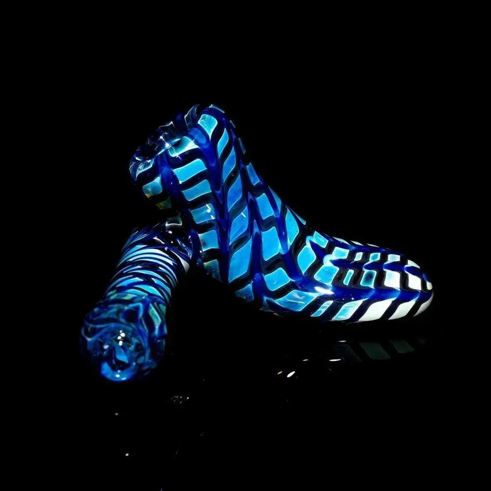 Blue glass hand pipe with white and black rake design on black background