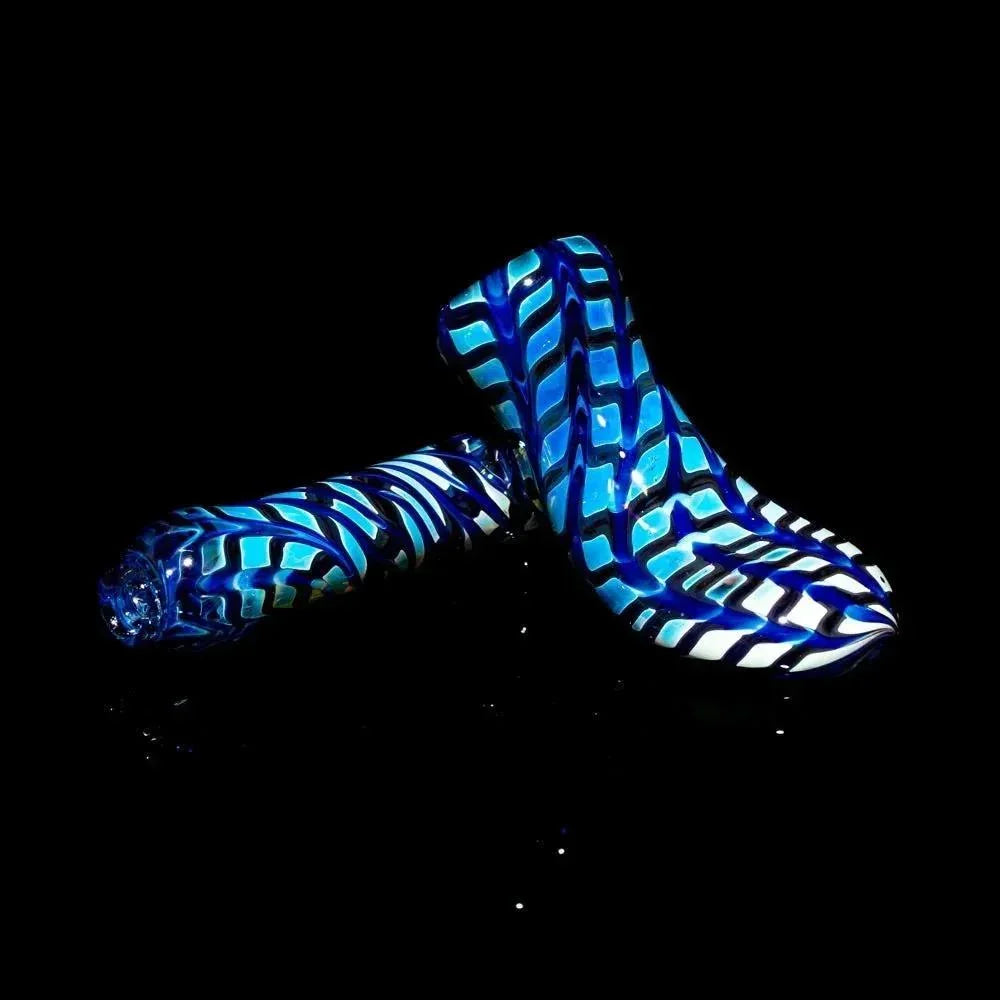 Hand-blown glass pipe with blue and white zigzag pattern on a black background