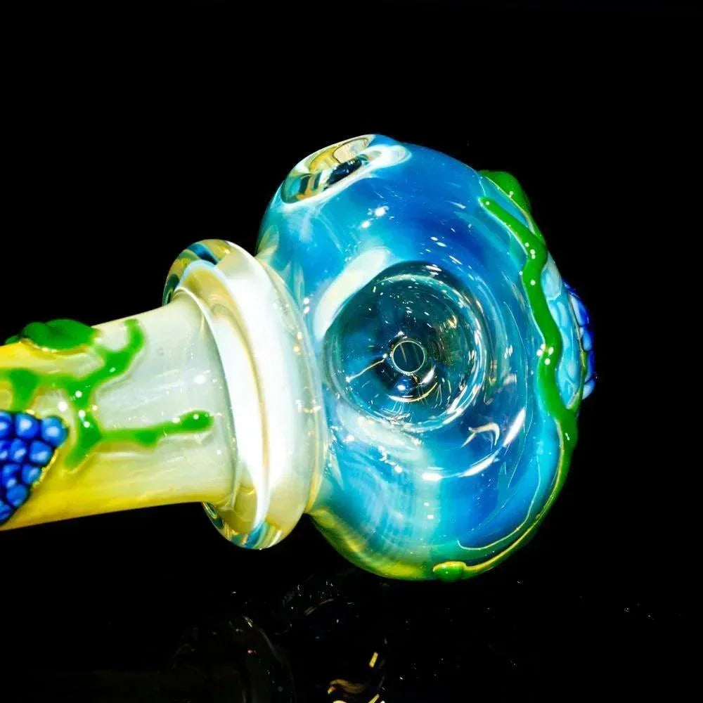 Colorful glass spoon pipe with blue, green, and yellow tree and flower designs