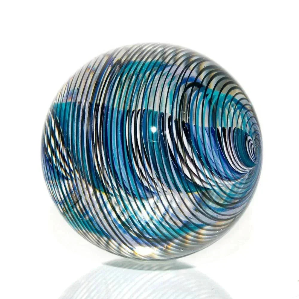 Handcrafted glass marble with blue, teal, and white linework design on a white background