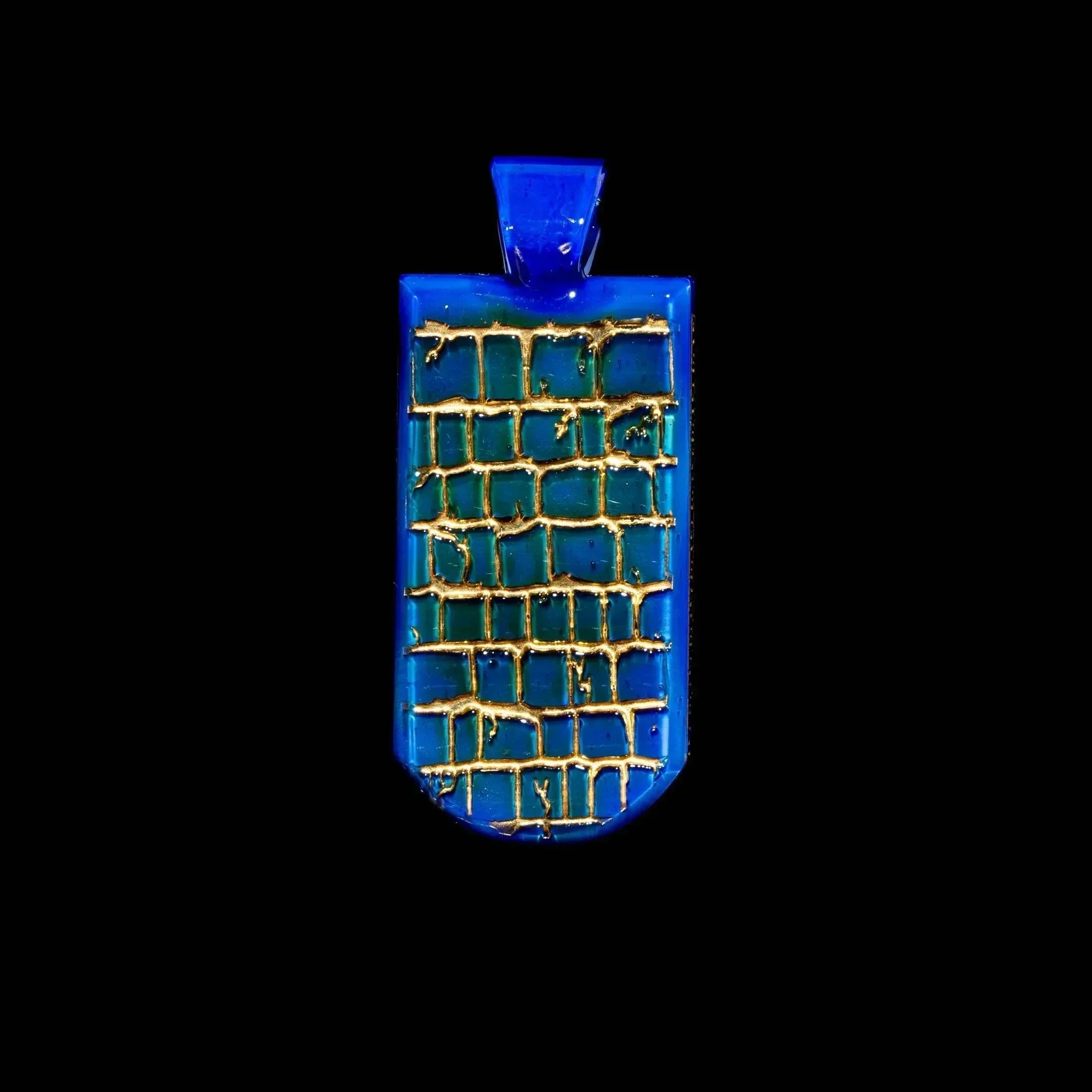 Blue glass pendant with gold geometric design on green peridot background, isolated on black