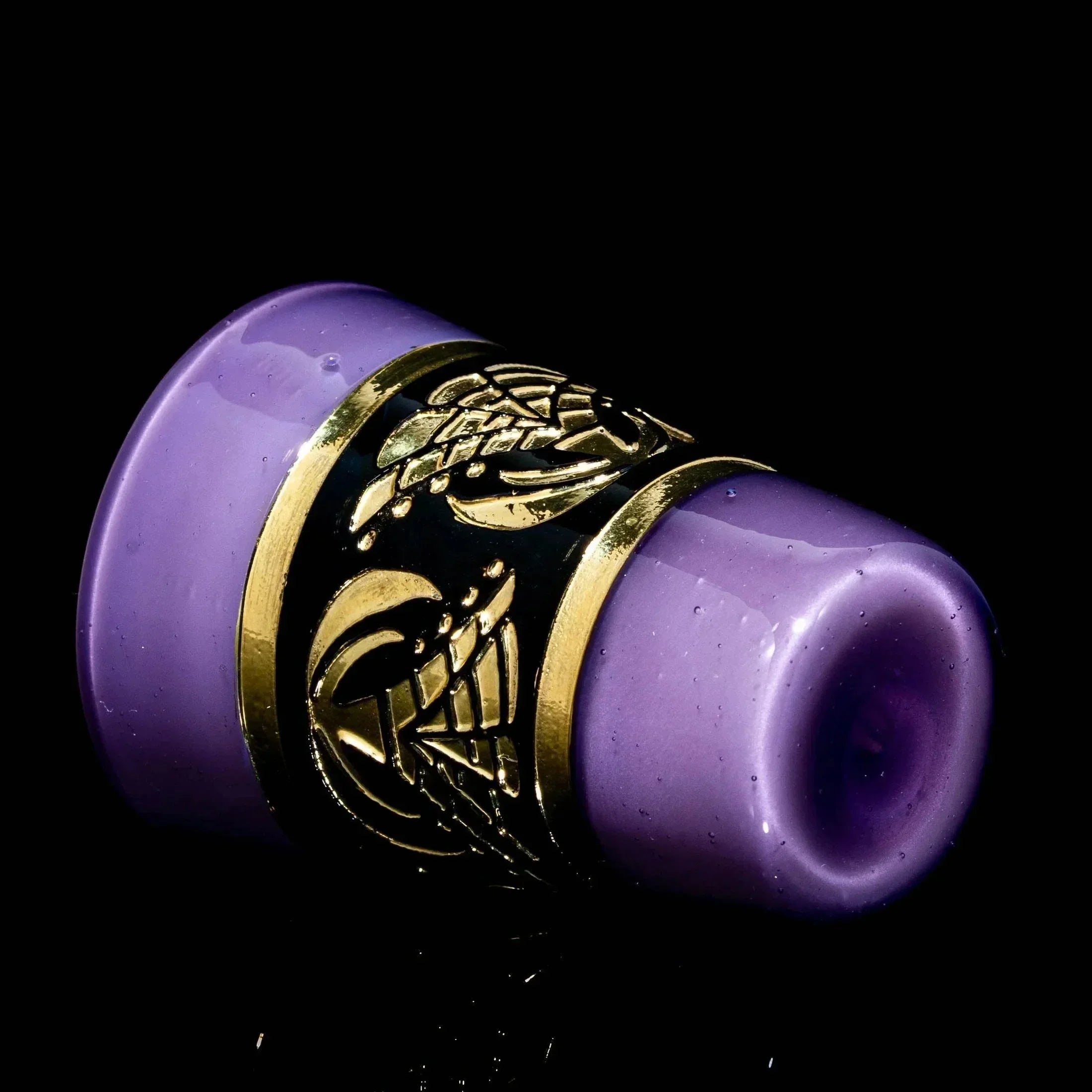 Purple satin glass shot glass with gold metallic decorative band on black background