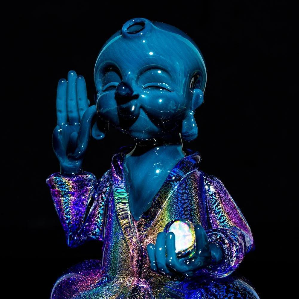 Blue glass Buddha figurine with iridescent robe and opal accent on black background