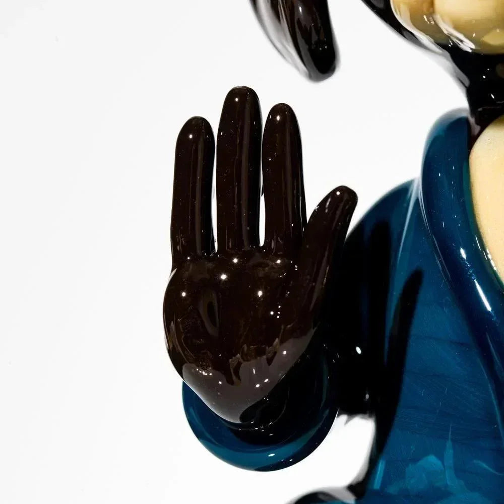 Handcrafted glass dog sculpture with raised black paw and blue robe detail