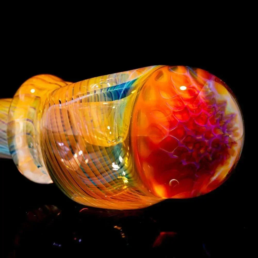 Close-up of a colorful honeycomb glass spoon pipe with vibrant orange and yellow accents.