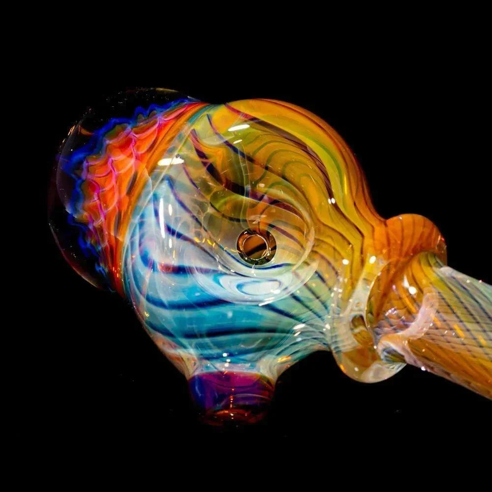 Colorful glass spoon pipe with honeycomb linework design on a black background