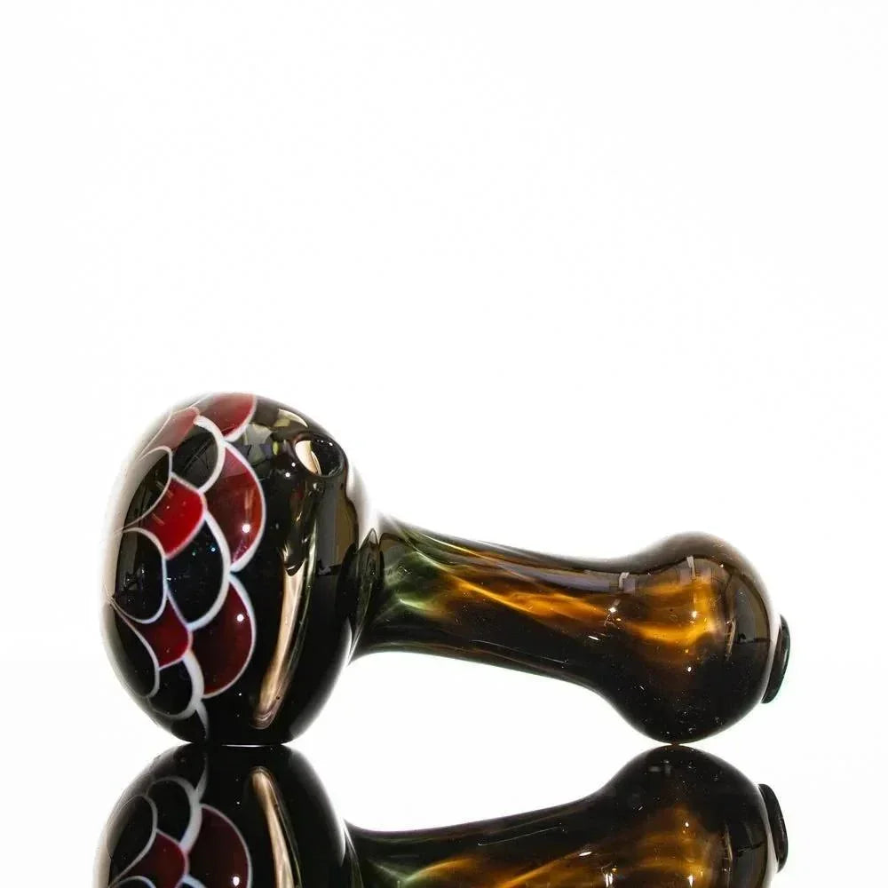 Handblown glass pipe with red and black floral design, amber stem, reflective surface