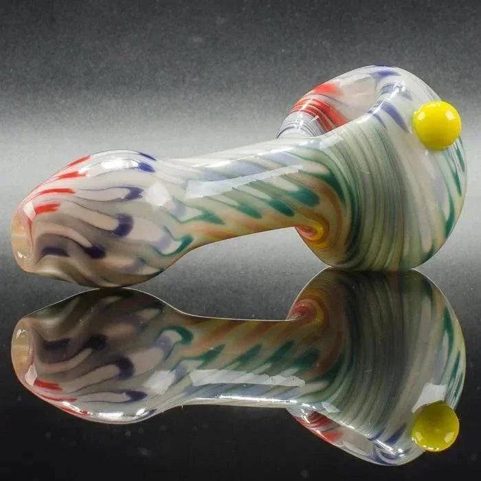 Colorful swirl glass pipe with yellow accent, reflective surface