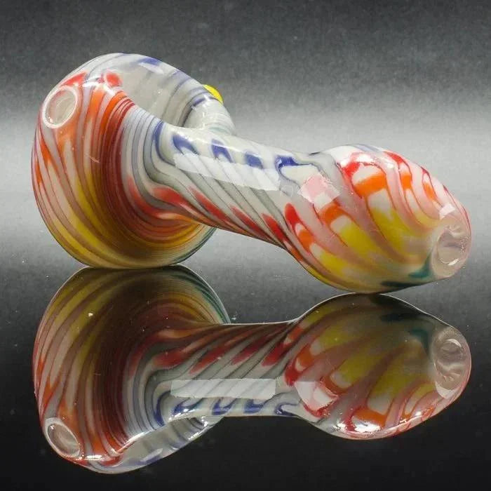 Colorful swirled glass pipe with red, yellow, blue, and white patterns on reflective surface