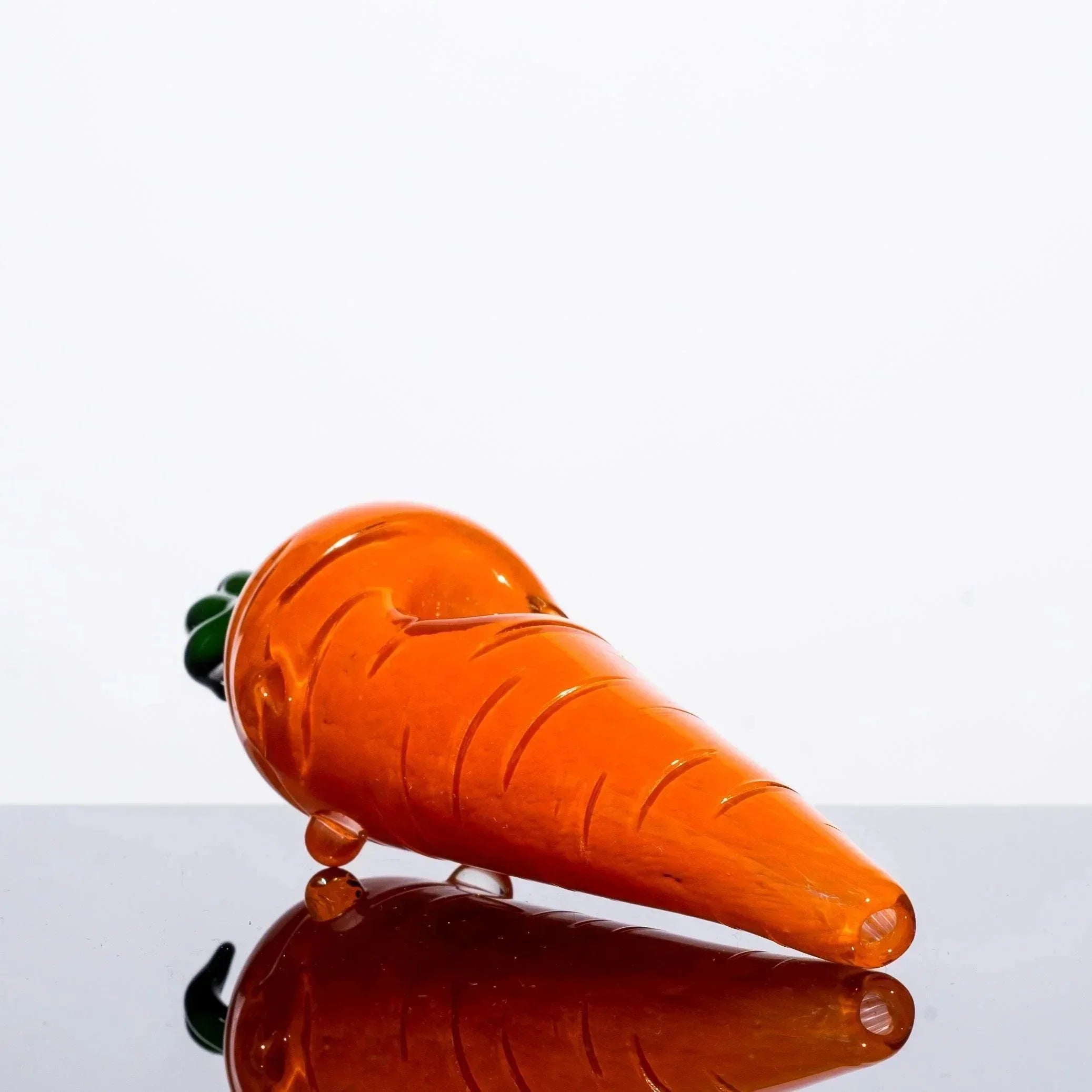 Hand-blown glass carrot pipe with green top, orange body, and reflective surface