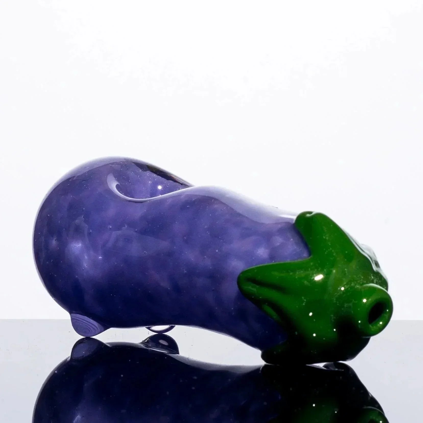 Purple and green glass eggplant pipe with glossy finish, reflective surface, heady glass art