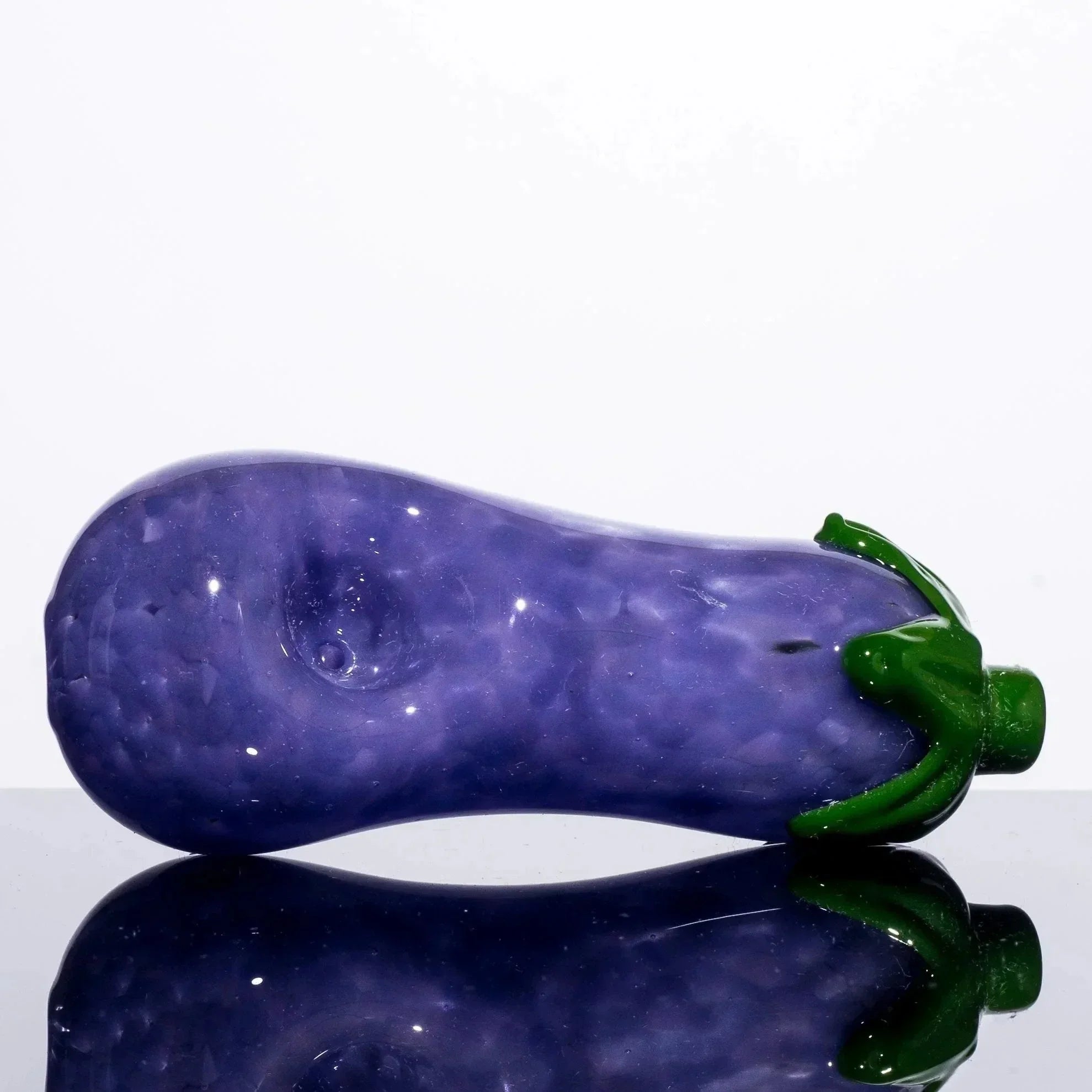 Purple glass eggplant pipe with green stem, reflective surface