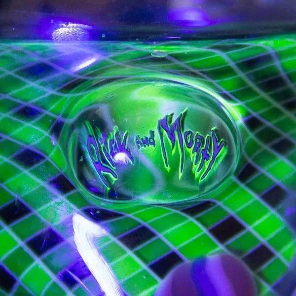 Vibrant green and purple Rick and Morty themed glass pipe with grid pattern under UV light