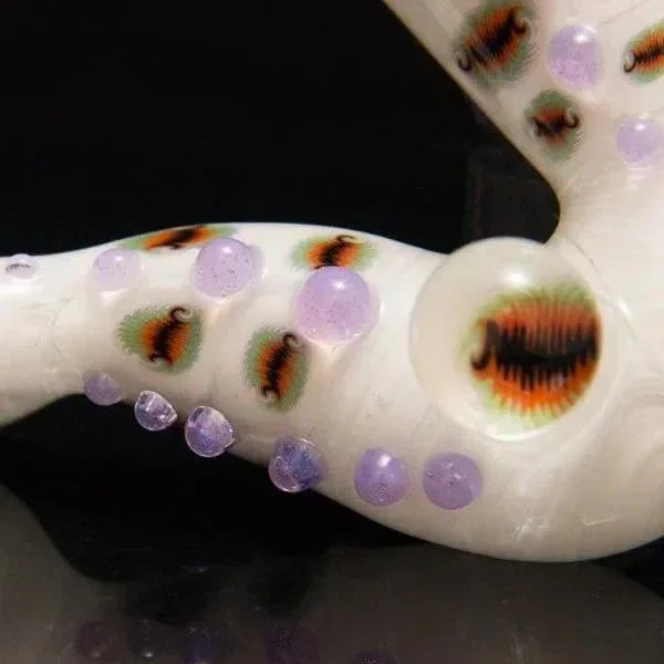 Heady glass pipe with purple accents and intricate eye designs, showcasing artisan craftsmanship.