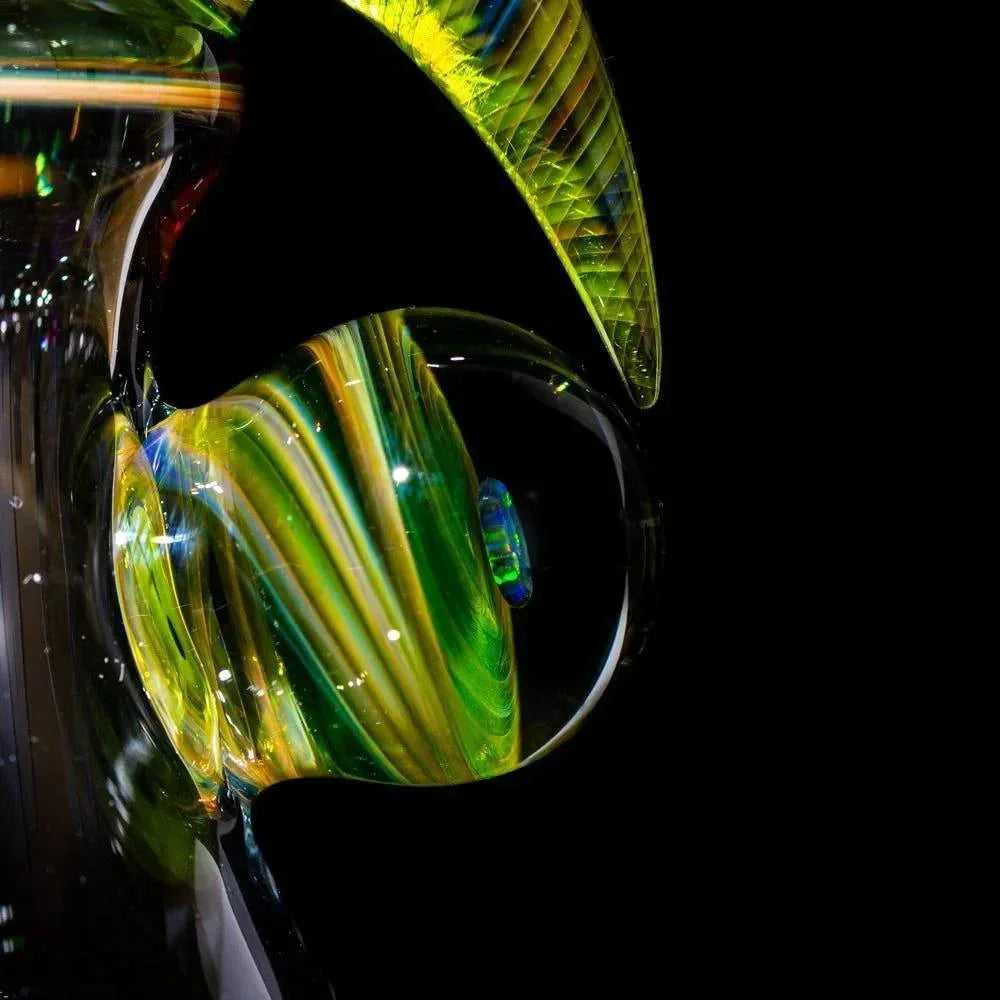 Vibrant green and yellow heady glass pipe with intricate swirls and dichroic accents, showcased against black.
