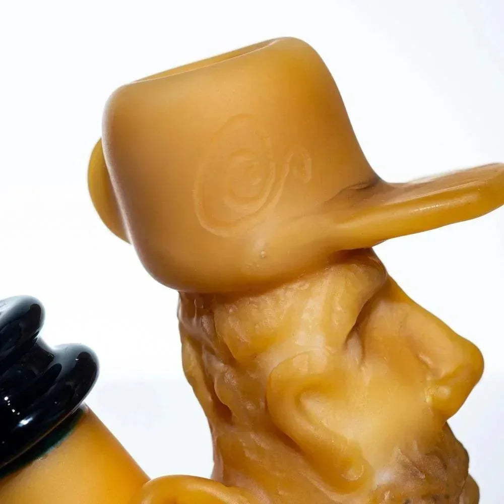 Close-up of a sculpted glass pipe featuring a whimsical character in a hat, yellow and black colors