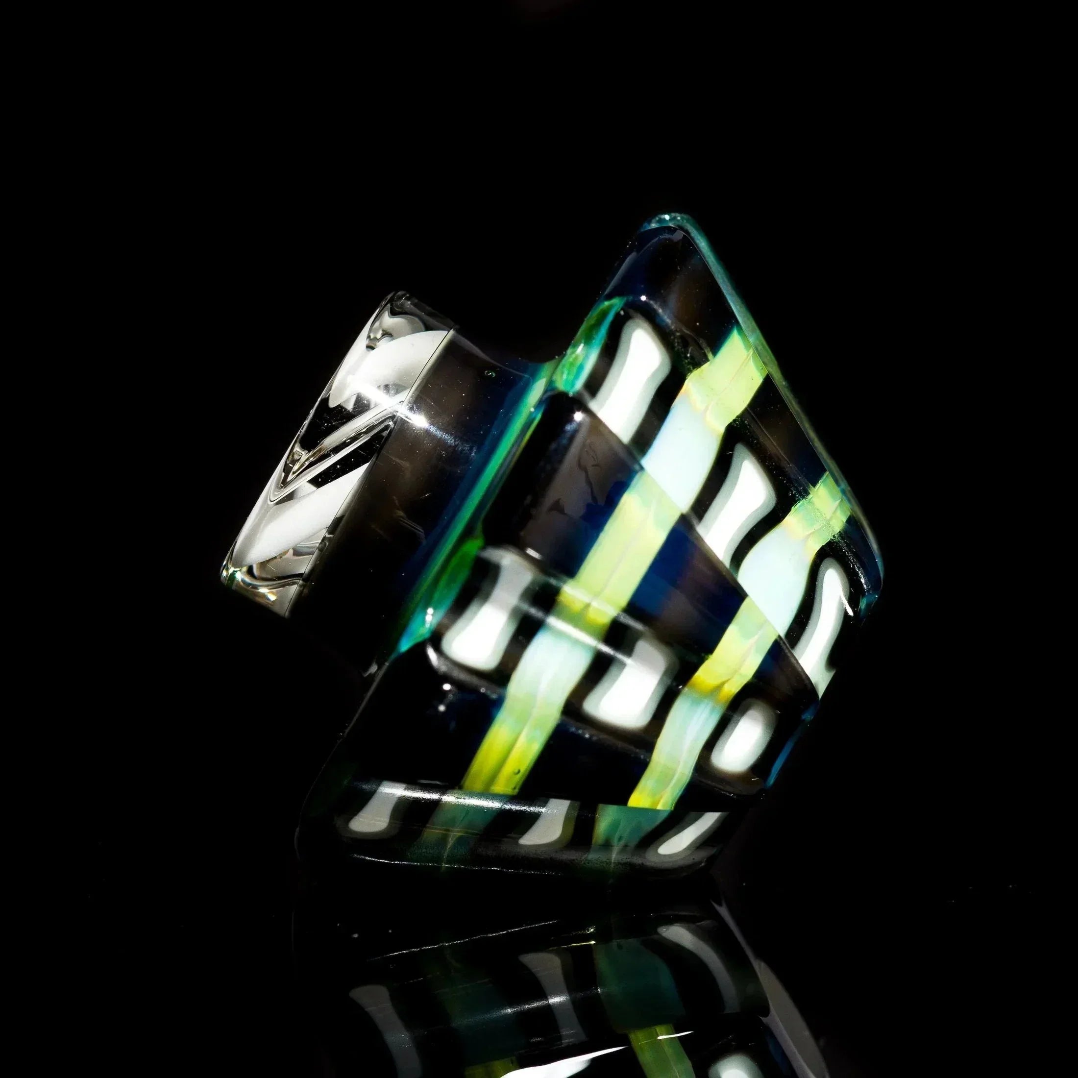 Colorful striped glass pipe with green, yellow, and blue swirls on black background