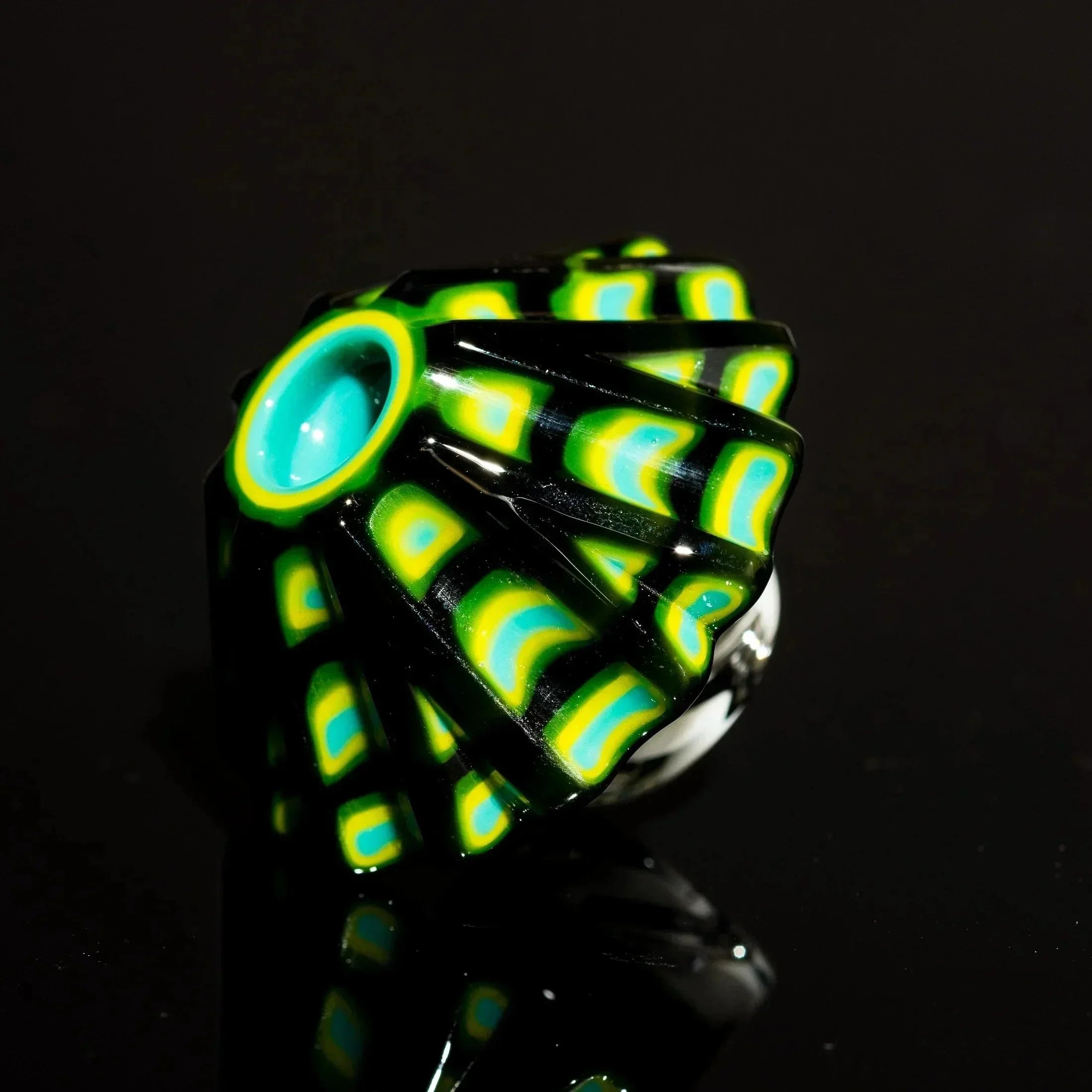 Heady glass pipe with vibrant green, yellow, and teal swirls on black base, reflective surface