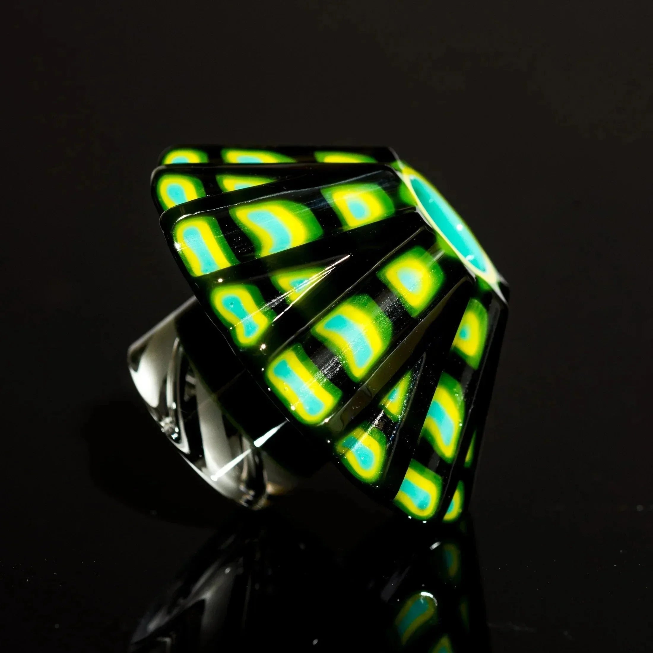 Vibrant green, yellow, and blue patterned glass pipe with black base, showcasing heady glass artistry