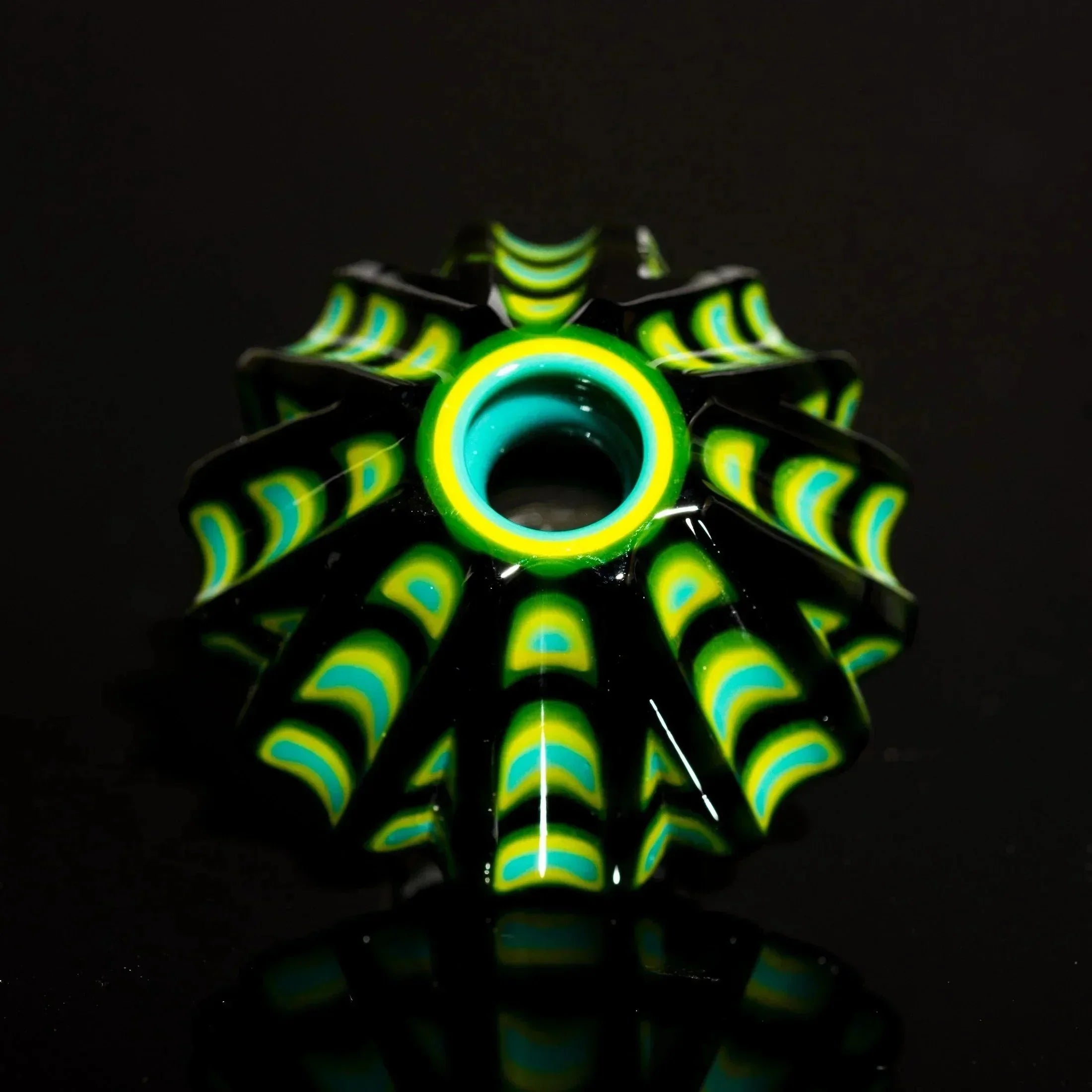 Vibrant green, yellow, and teal glass pipe bowl with intricate layered design on black background